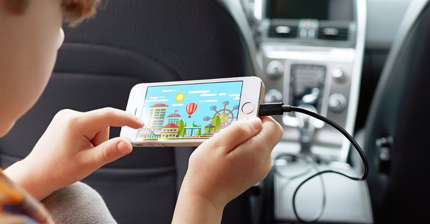 Seorang anak di mobil menggunakan ponsel yang sedang di-charge. Seorang anak di mobil menggunakan ponsel yang sedang di-charge.