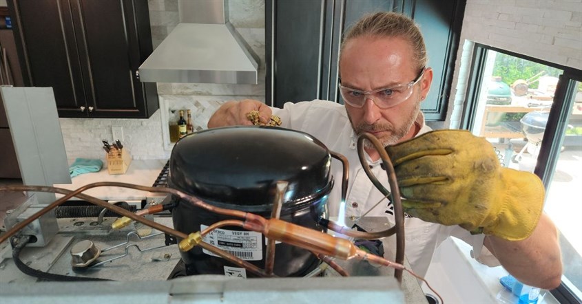 Gambar teknisi yang sedang memasang kompresor inverter kulkas Gambar teknisi yang sedang memasang kompresor inverter kulkas